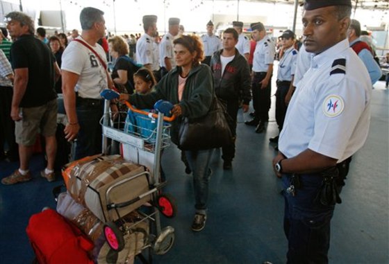 A Romanian gypsy family with their belongings, is escorted by French police officers to the check-in desk at Charles de Gaulle airport near Paris on Friday.